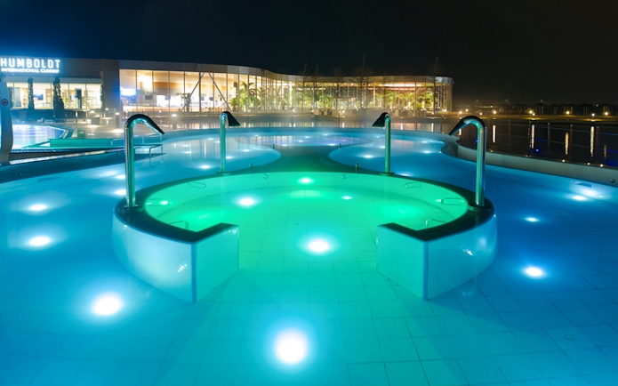 Outdoor pool at the Palm Zone, Therme Bucharest, illuminated at night.