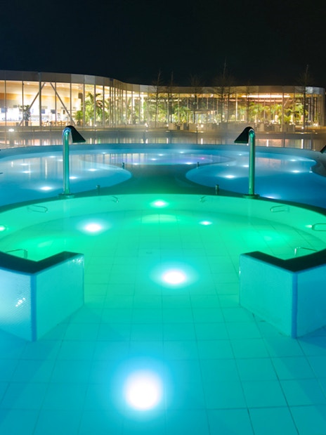 Outdoor pool at the Palm Zone, Therme Bucharest, illuminated at night.