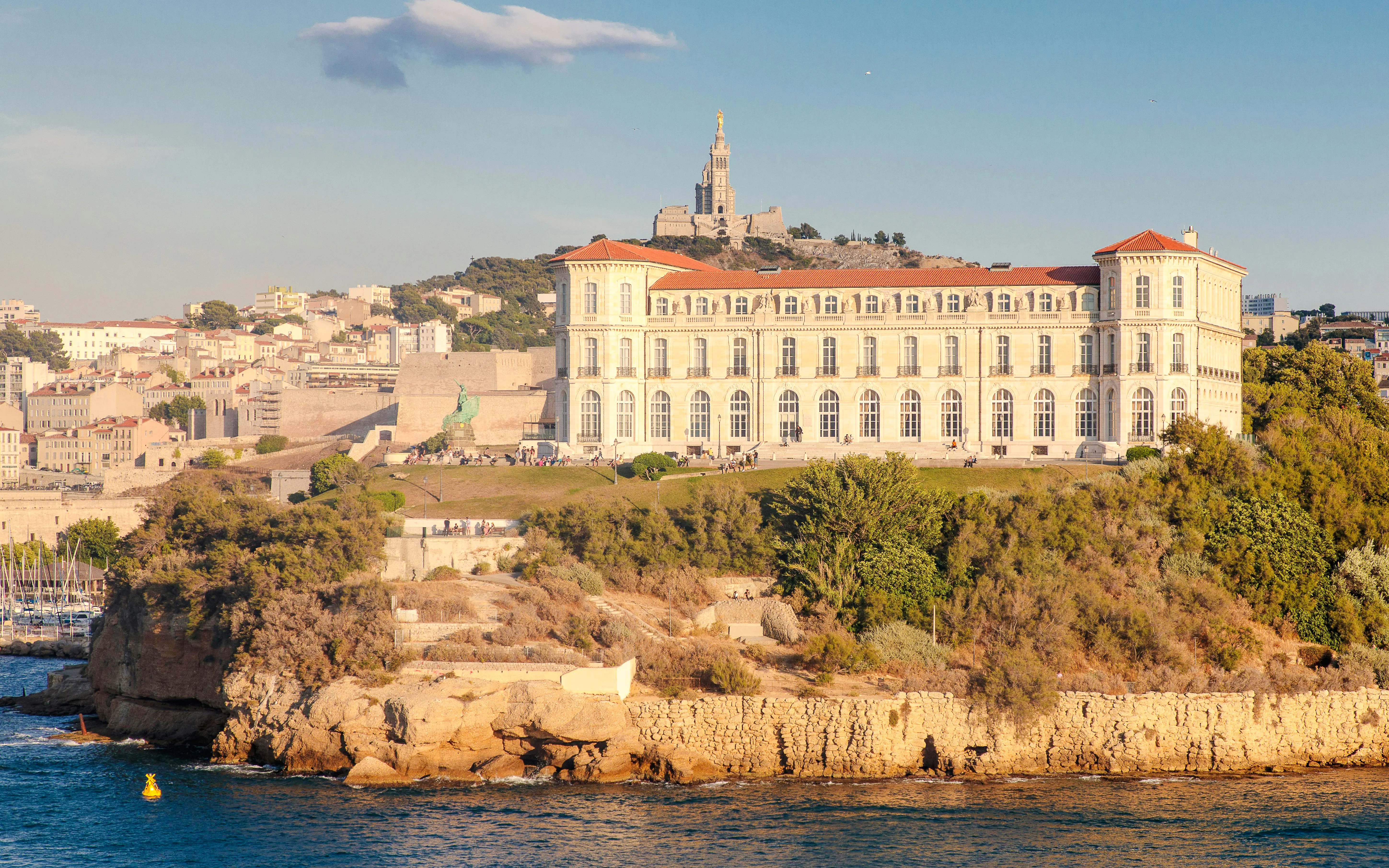 Le Palais du Pharo overlooking the sea in Marseille, France, with Notre-Dame de la Garde in the background.