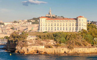 Le Palais du Pharo overlooking the sea in Marseille, France, with Notre-Dame de la Garde in the background.