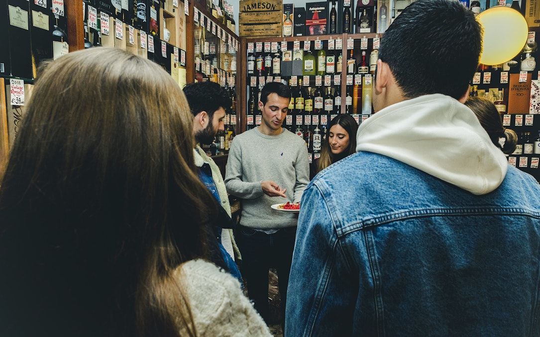 Group tasting wine and food in a Porto shop during a tour.