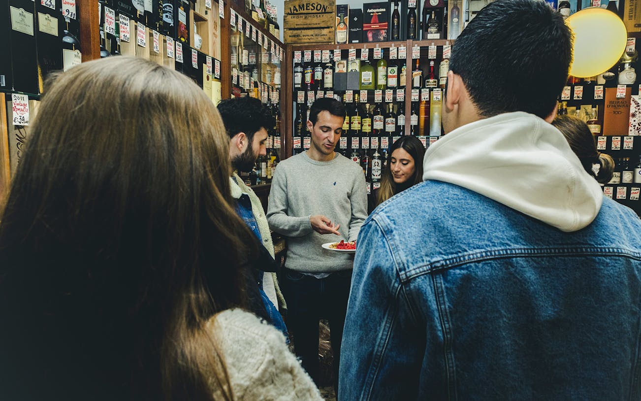 Group tasting wine and food in a Porto shop during a tour.