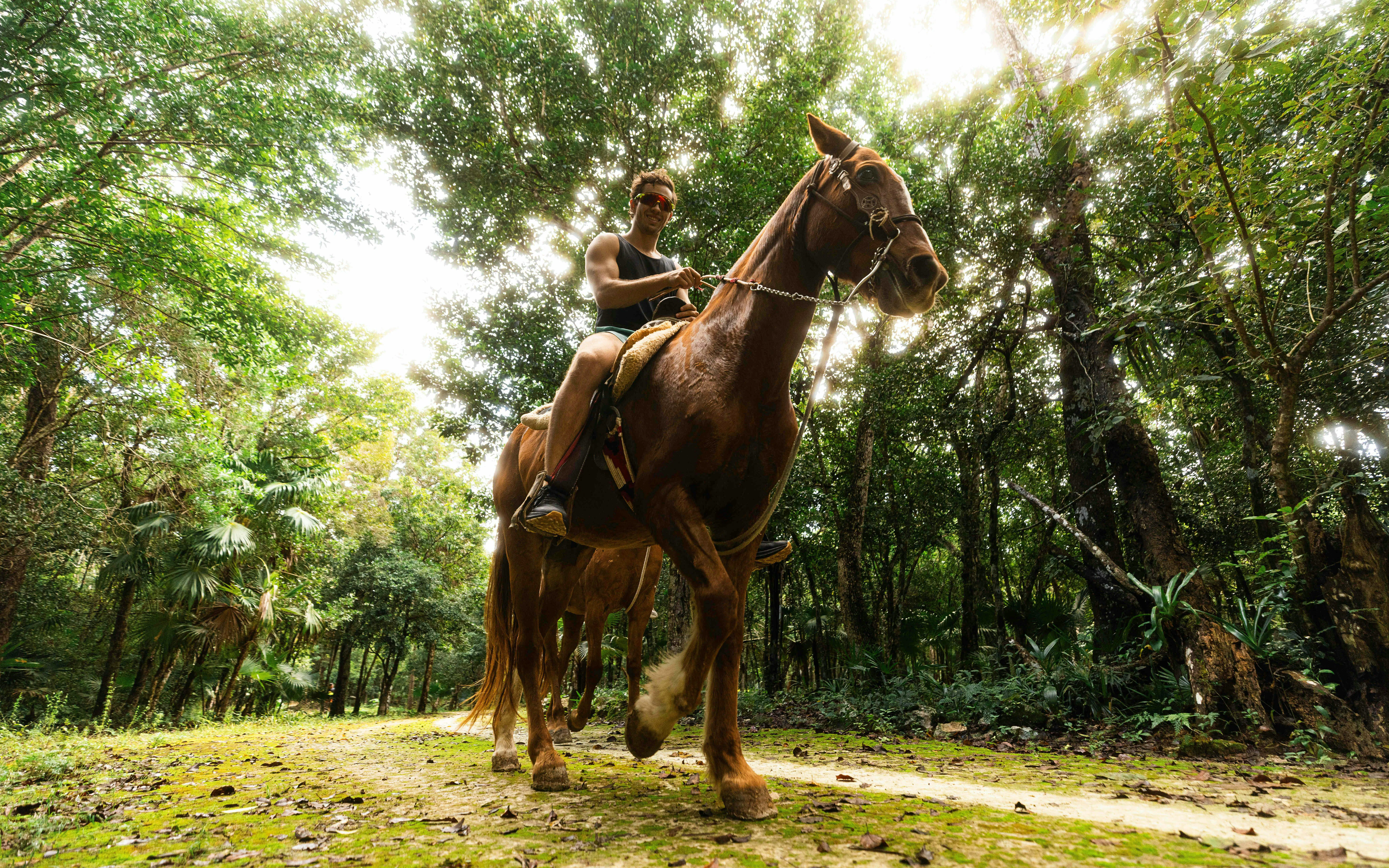 Horseback riding through lush forest at Cancun Extreme Adventuring Park.