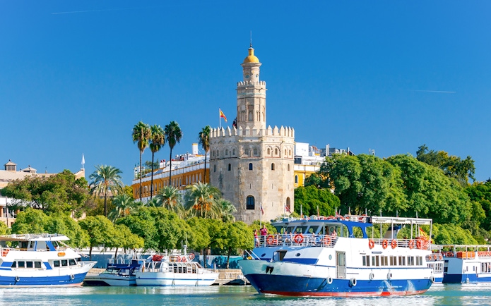 Cruise boats on the Guadalquivir River with Torre del Oro in Seville.