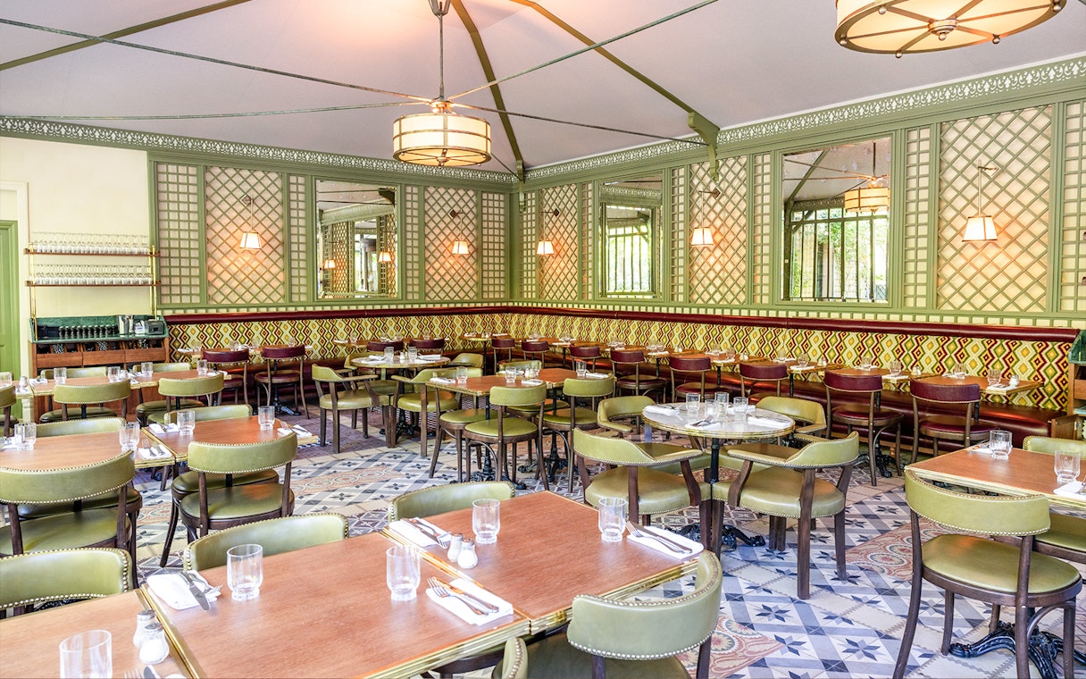 Elegant dining area set for Flottille's snack & go experience, featuring patterned walls and green chairs.