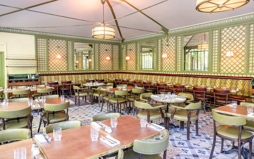 Elegant dining area set for Flottille's snack & go experience, featuring patterned walls and green chairs.