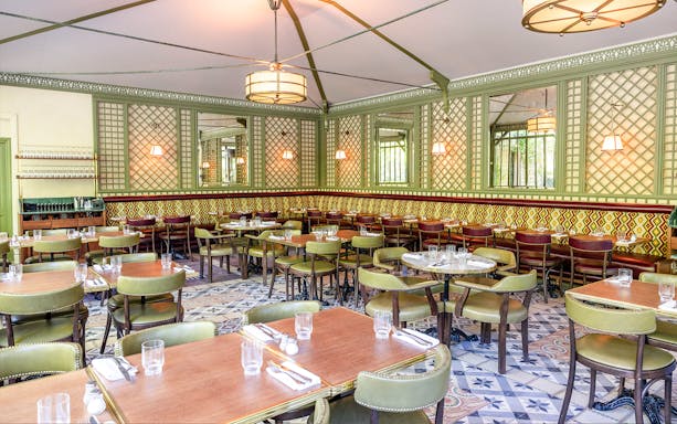 Elegant dining area set for Flottille's snack & go experience, featuring patterned walls and green chairs.