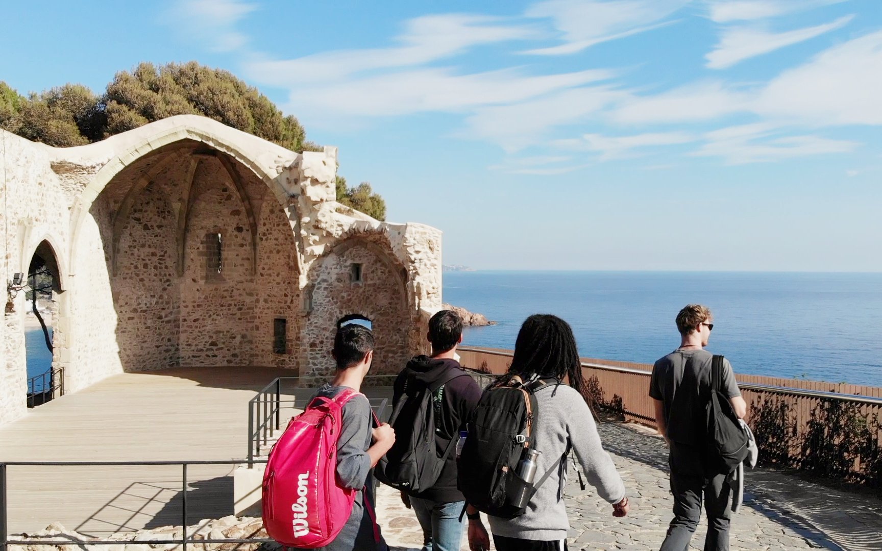 Visitors exploring the ruins of Esglesia Vella de Sant Vicenc in Tossa de Mar, Catalonia, with sea view.