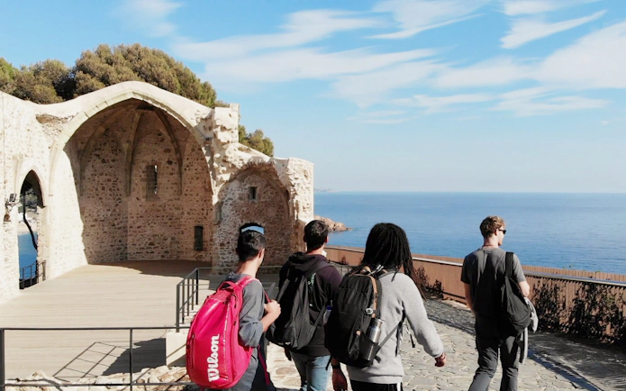 Visitors exploring the ruins of Esglesia Vella de Sant Vicenc in Tossa de Mar, Catalonia, with sea view.
