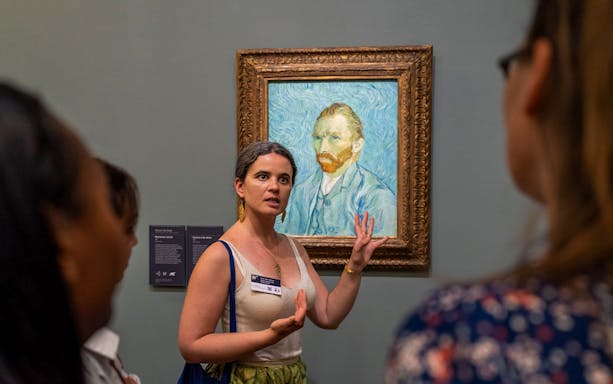 Tour guide explaining Van Gogh painting at Musée d’Orsay, Paris.