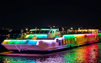 Colorful Riverside Kinlen Cruise boat illuminated at night on the Chao Phraya River, Bangkok.
