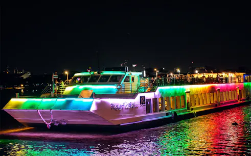 Colorful Riverside Kinlen Cruise boat illuminated at night on the Chao Phraya River, Bangkok.
