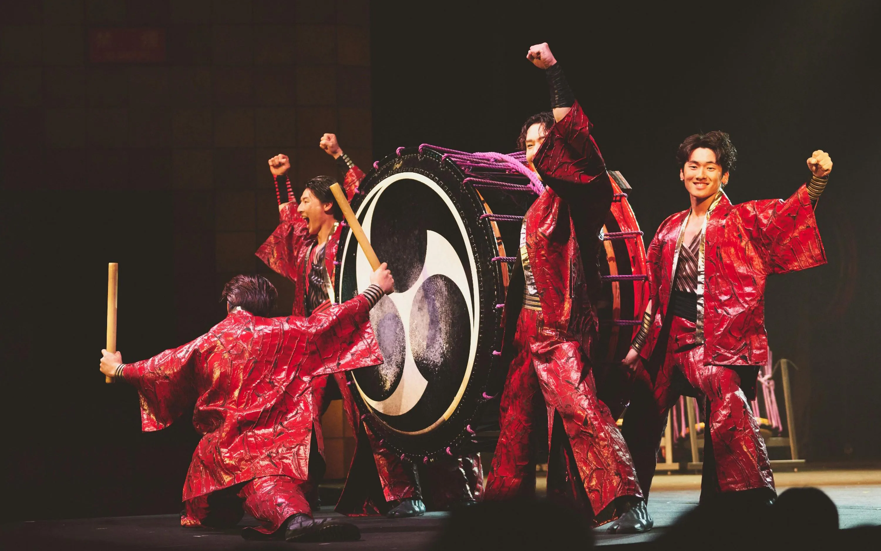 Performers in red costumes playing a large drum at DRUM TAO Theater Kyoto.