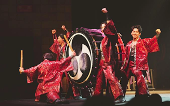 Performers in red costumes playing a large drum at DRUM TAO Theater Kyoto.