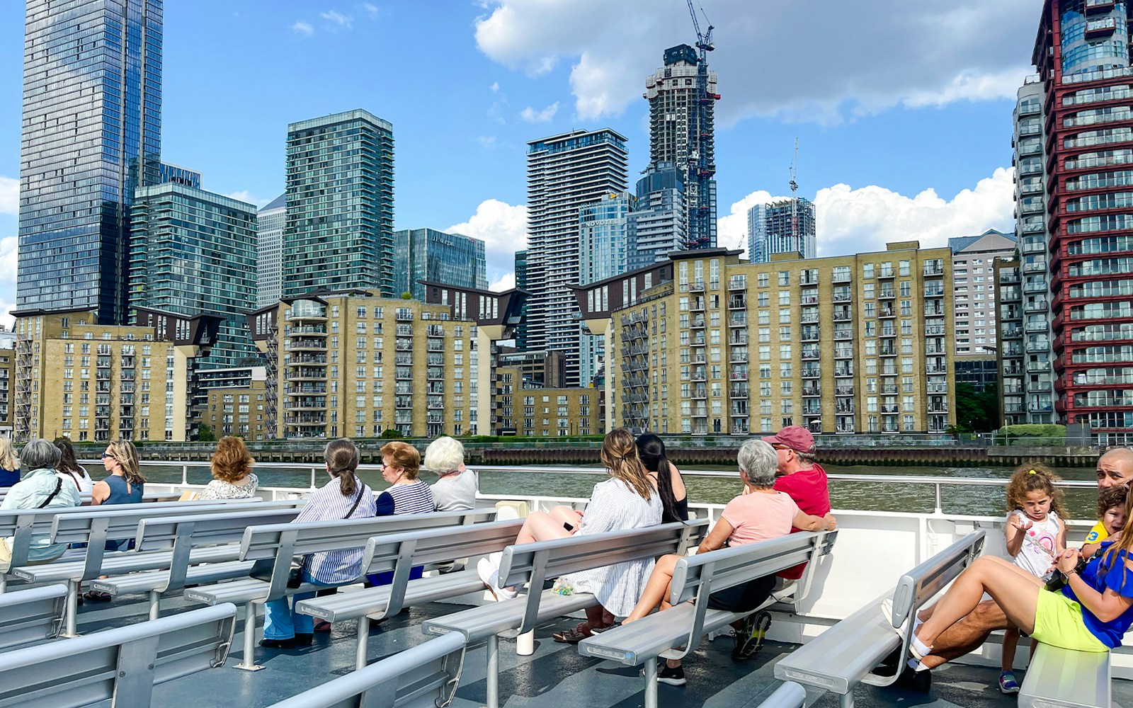 London Sightseeing Cruise passing Canary Wharf skyscrapers on the Thames River.