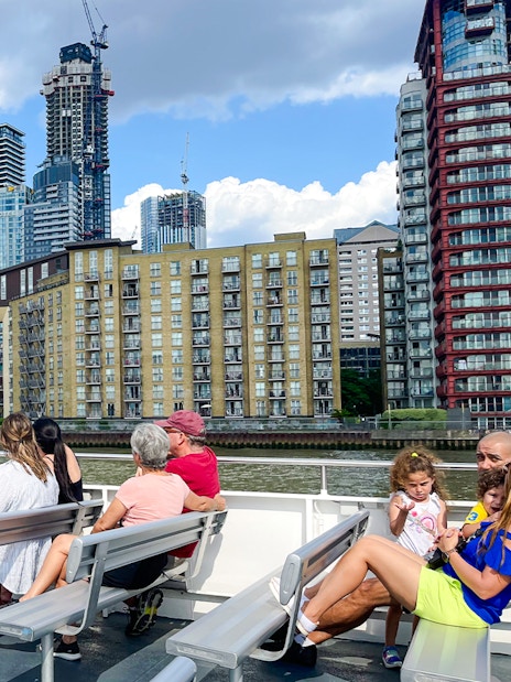 Passengers on a London sightseeing cruise view Canary Wharf skyline.