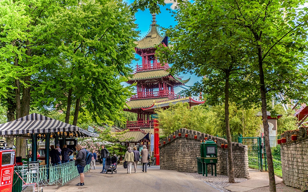 Pagoda in Tivoli Gardens, Copenhagen, surrounded by trees and visitors strolling nearby.