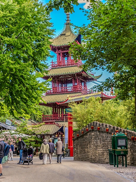 Pagoda in Tivoli Gardens, Copenhagen, surrounded by trees and visitors strolling nearby.