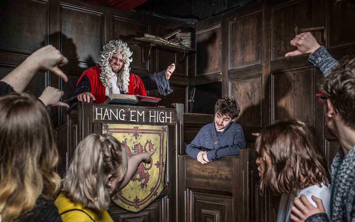 Judge in period costume presides over mock trial at Edinburgh Dungeon Tour.