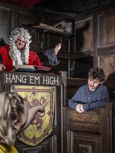 Judge in period costume presides over mock trial at Edinburgh Dungeon Tour.