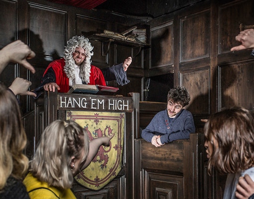 Judge in period costume presides over mock trial at Edinburgh Dungeon Tour.