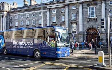 Dublin Express bus at Custom House Quay with historic building in background.