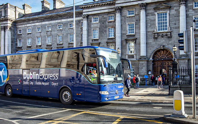 Dublin Express bus at Custom House Quay with historic building in background.