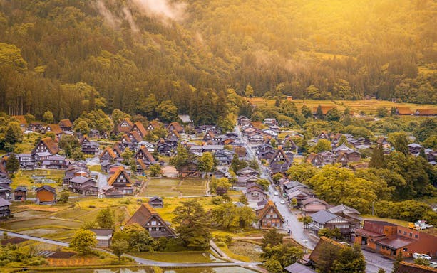 Shirakawago village with traditional gassho-zukuri houses surrounded by lush greenery, Japan.
