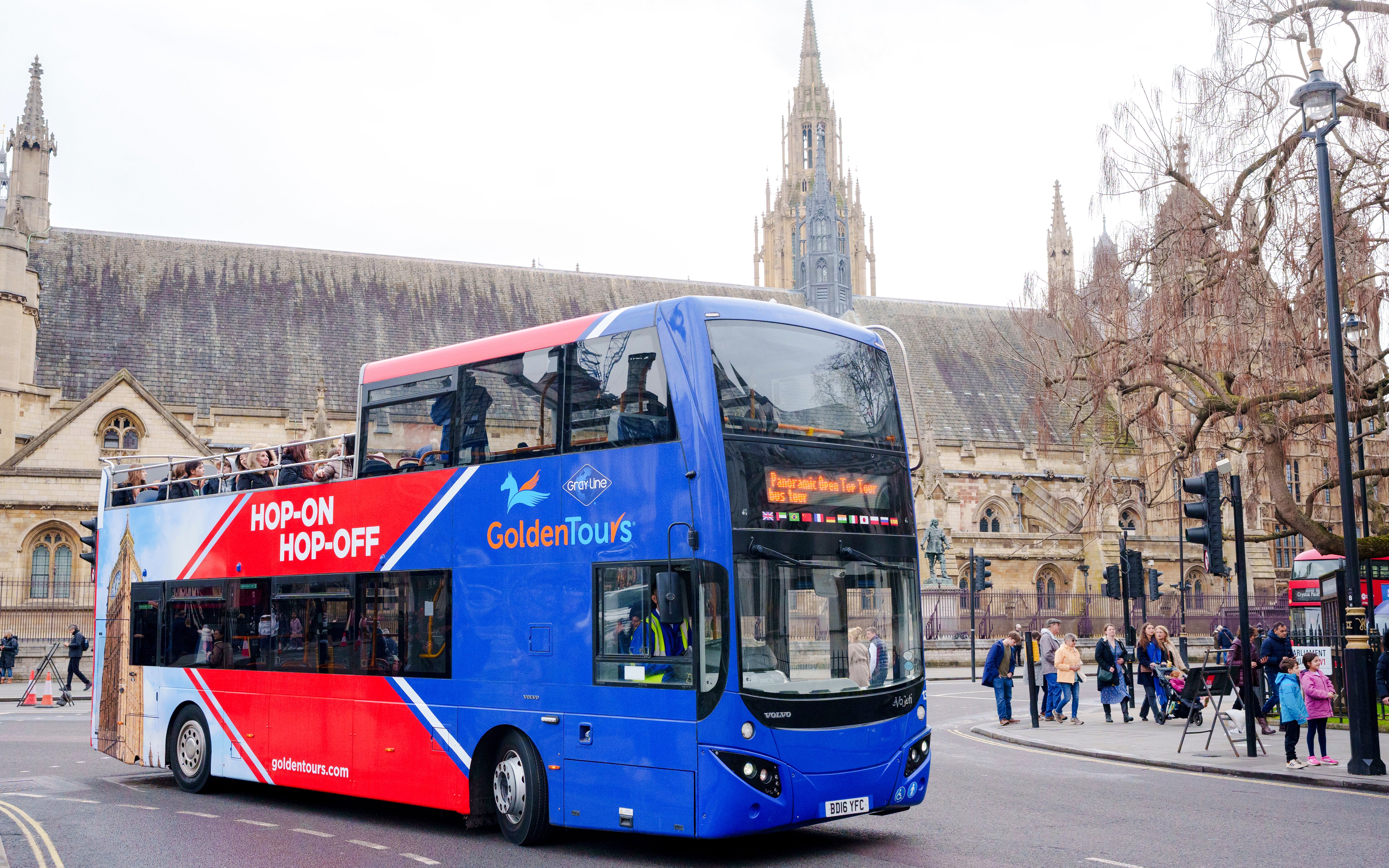 Golden Tours hop-on hop-off bus in front of historic building in city.