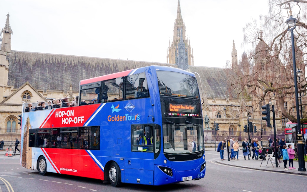 Golden Tours hop-on hop-off bus in front of historic building in city.