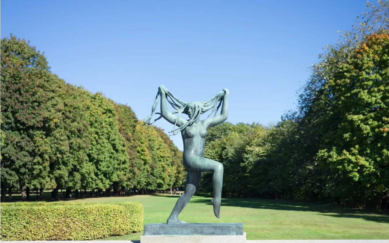 Sculpture of a woman in Vigeland Park, Oslo, surrounded by trees.
