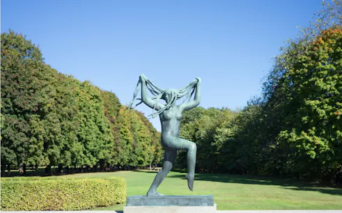Sculpture of a woman in Vigeland Park, Oslo, surrounded by trees.