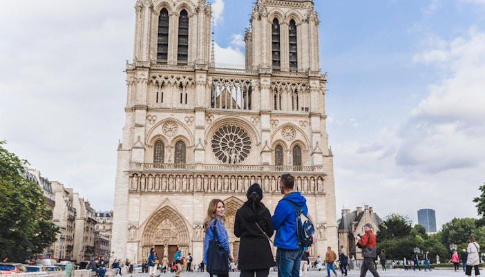 Tour guide with tourists in front of Notre Dame Cathedral, Paris.