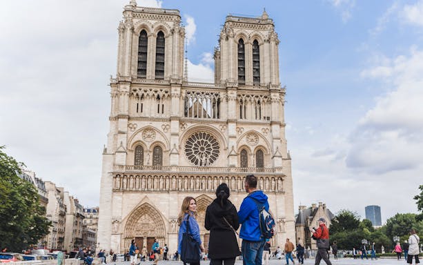 Tour guide with tourists in front of Notre Dame Cathedral, Paris.