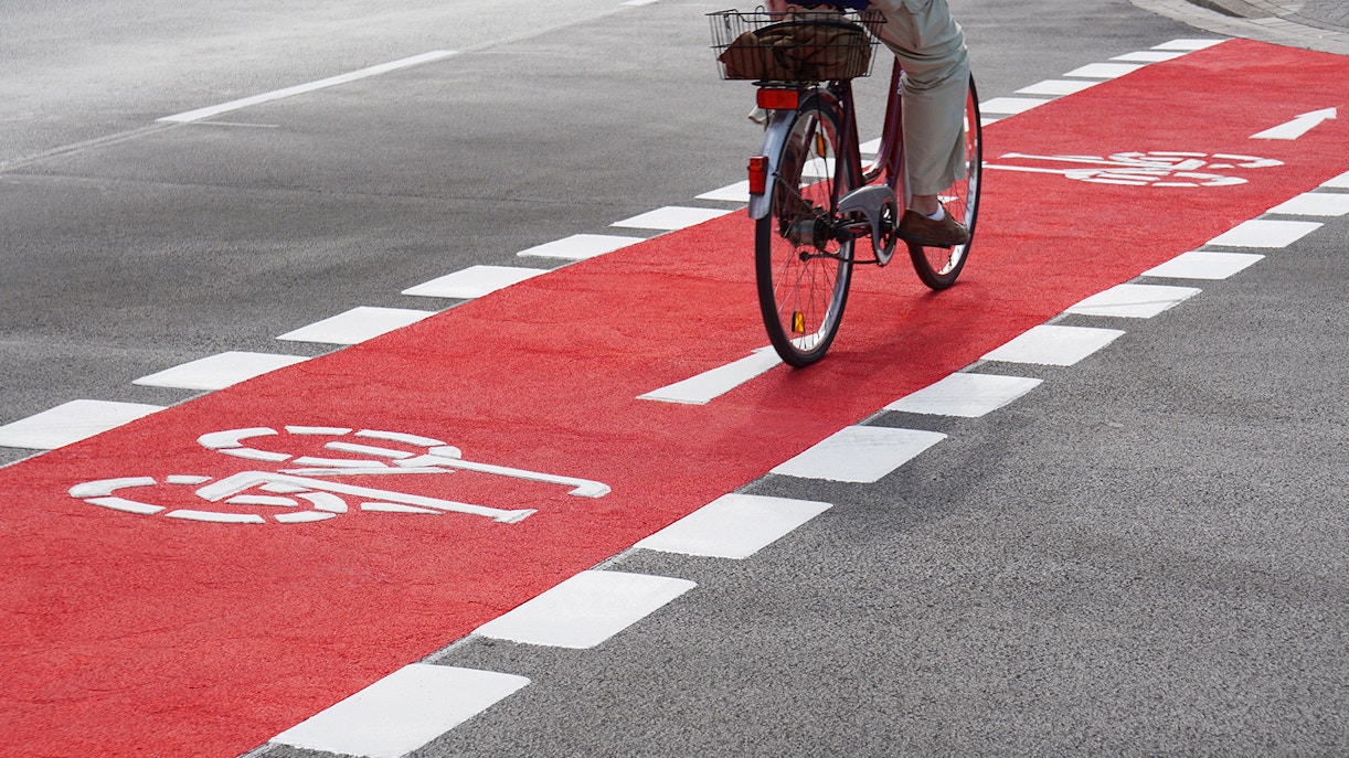 Cyclist on red designated cycling path with bike symbols.