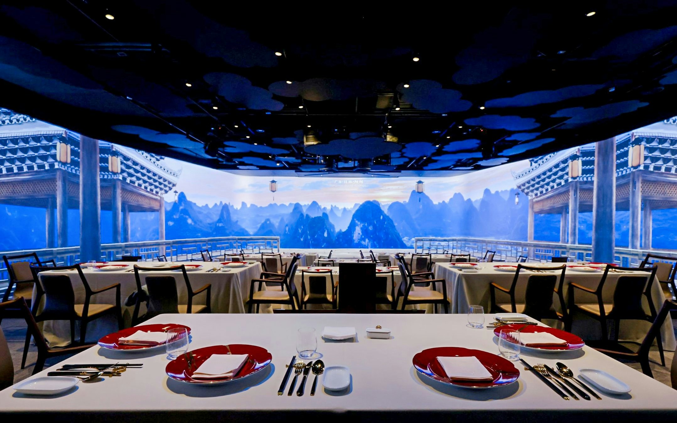 Immersive Chinese restaurant with mountain view backdrop and elegantly set tables.