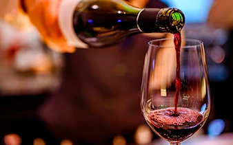 Pouring red wine into a glass at Homero Manzi Tango show dinner.