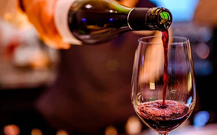 Pouring red wine into a glass at Homero Manzi Tango show dinner.