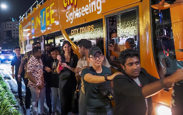 People boarding the FunVee party bus for a pub crawl in Singapore at night.