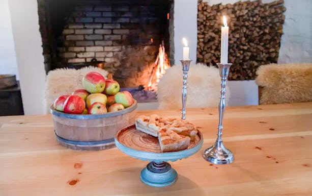 Apples and apple cake on a table by a fireplace at Spildegarden farm.