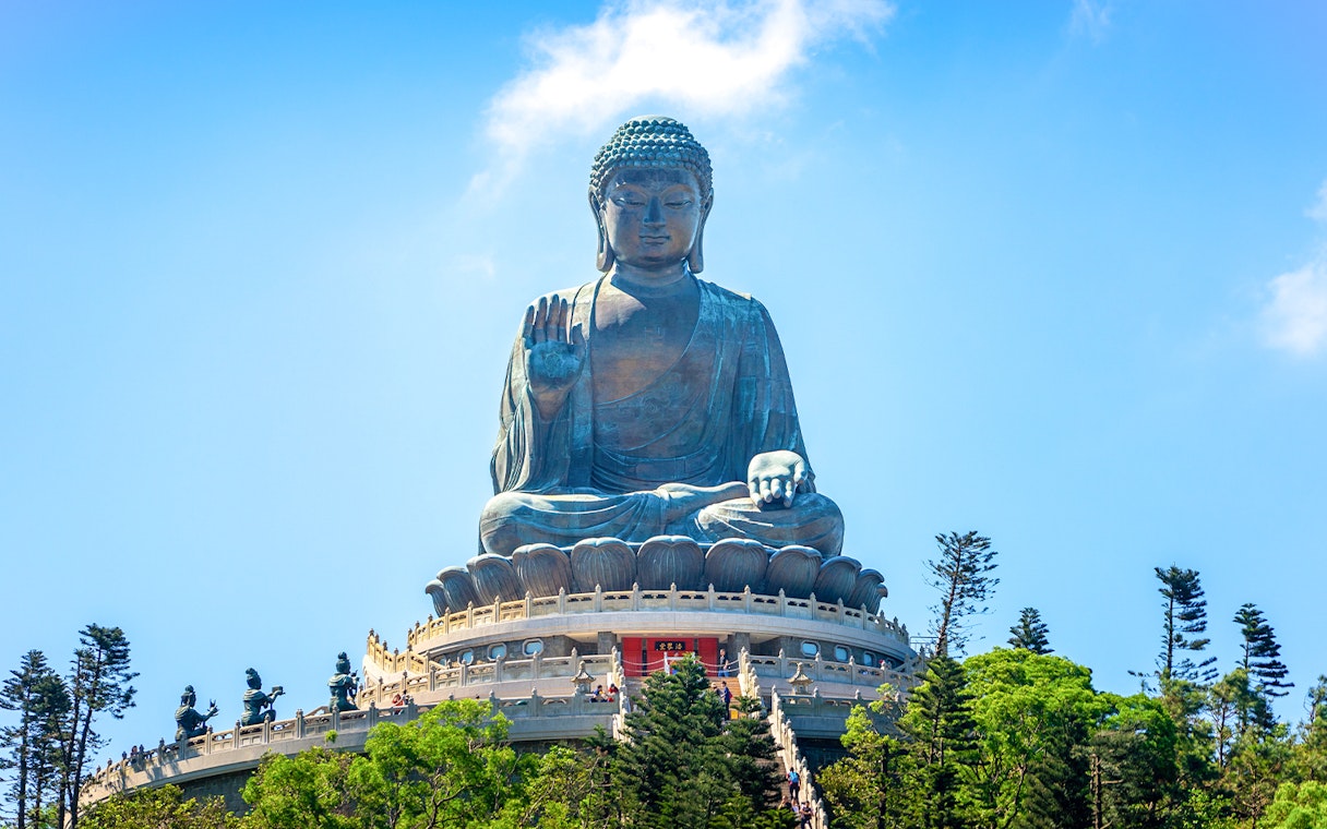 Tian Tan Buddha statue on Lantau Island, Hong Kong, viewed from below with surrounding trees.