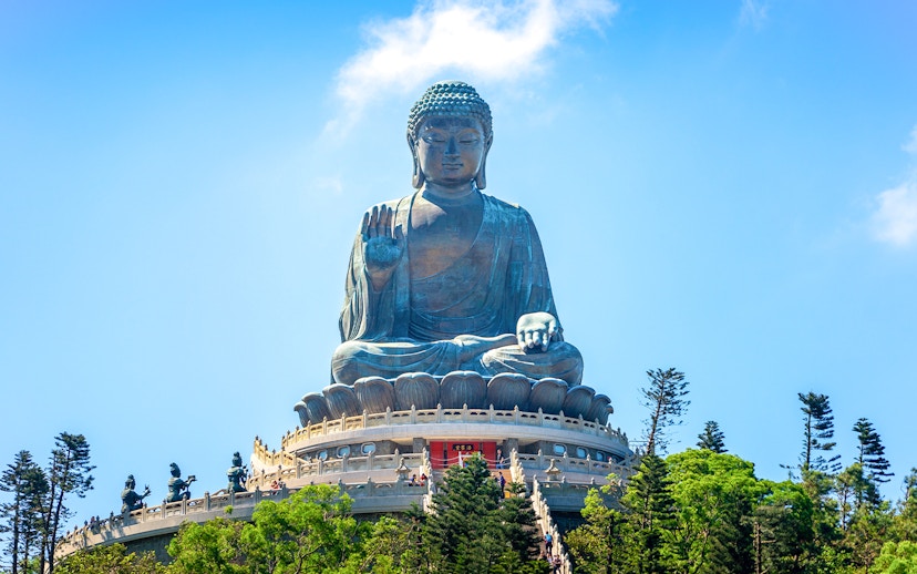 Tian Tan Buddha statue on Lantau Island, Hong Kong, viewed from below with surrounding trees.