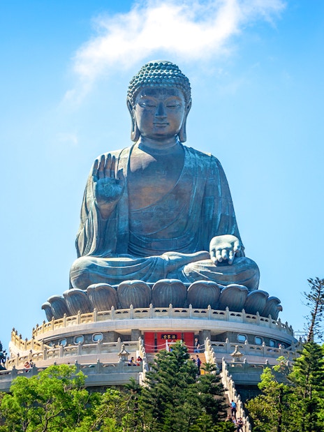 Tian Tan Buddha statue on Lantau Island, Hong Kong, viewed from below with surrounding trees.