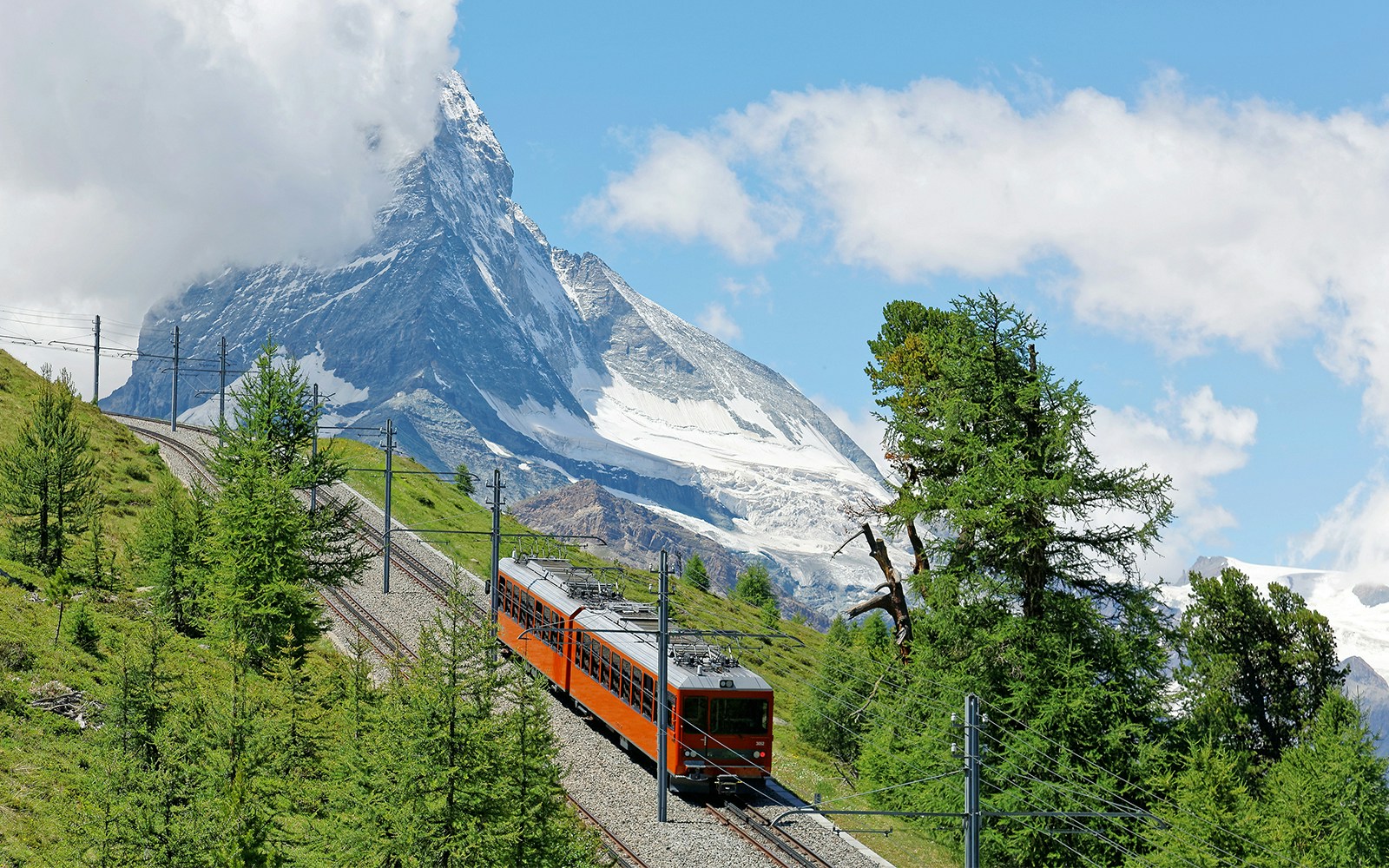 Gornergrat Railway ascending Swiss Alps with Matterhorn view.