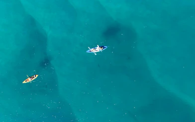 Kayakers paddling in clear blue waters during Gold Coast snorkeling tour.