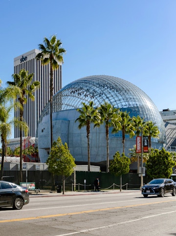 Academy Museum of Motion Pictures with glass dome and palm trees in Los Angeles.