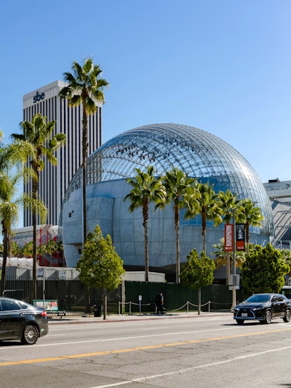 Academy Museum of Motion Pictures with glass dome and palm trees in Los Angeles.