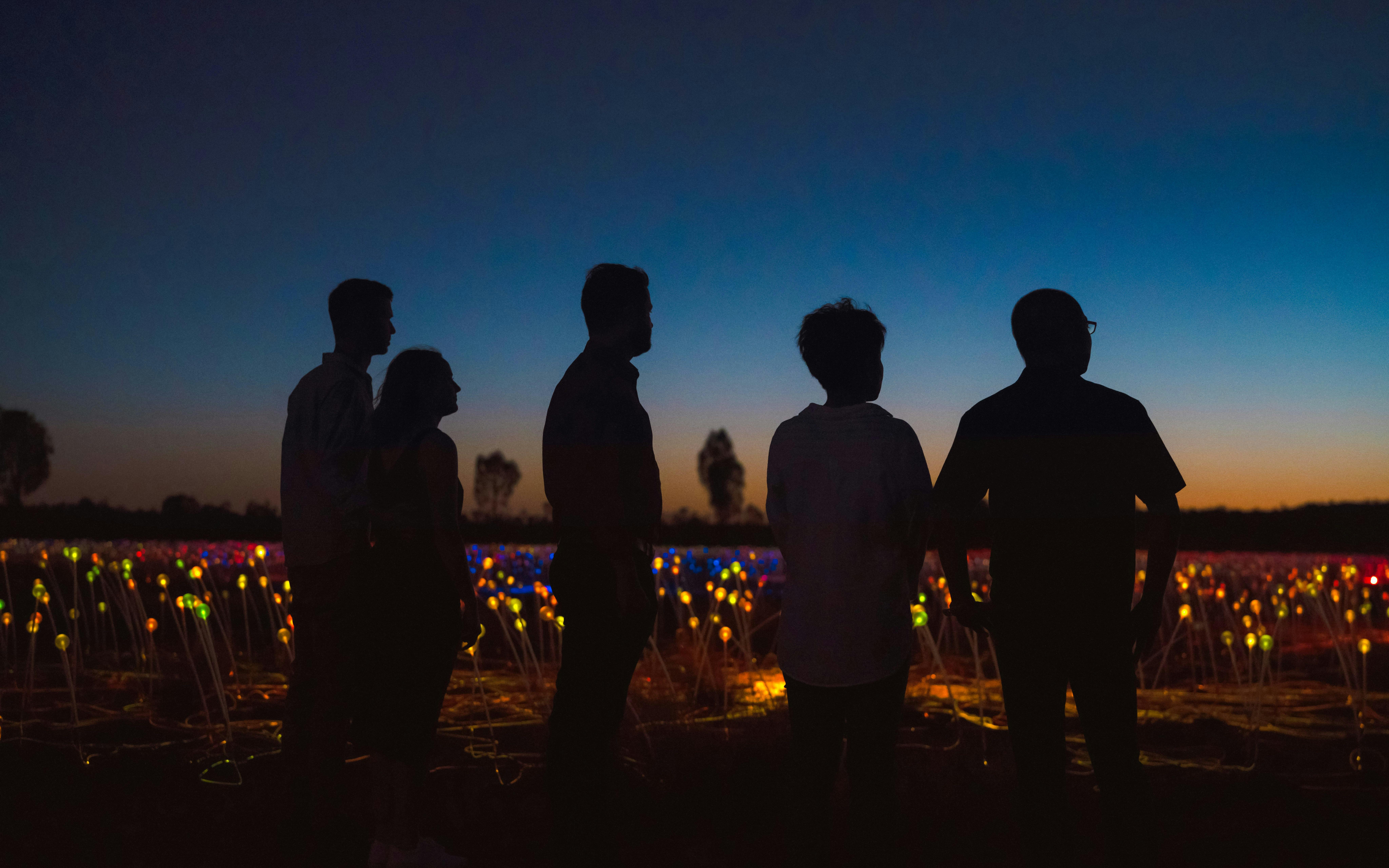 Visitors enjoying the Field of Light installation at sunrise near Uluru.