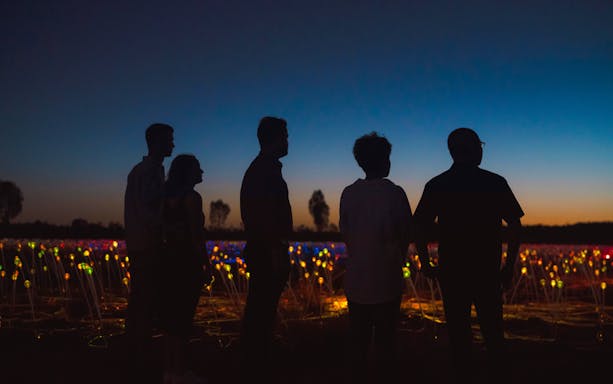 Visitors enjoying the Field of Light installation at sunrise near Uluru.