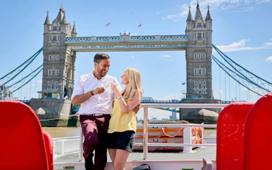 Guests enjoying drinks on a cruise with Tower Bridge in the background, London.